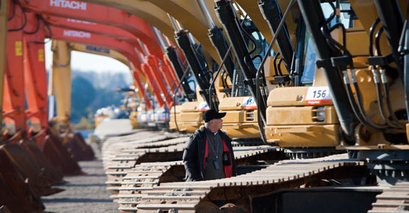 A prospective buyer takes a look at Hitachi and Komatsu hydraulic excavators at the auction site