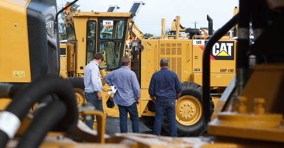 Customers inspecting Caterpillar heavy equipment at a Ritchie Bros. auction site